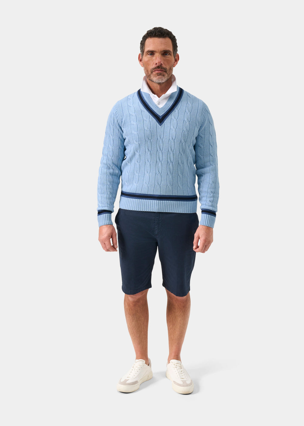 Steel blue cotton cable knit V-neck jumper with dark navy trim, regular fit, worn over white shirt with navy shorts and white sneakers, front view
