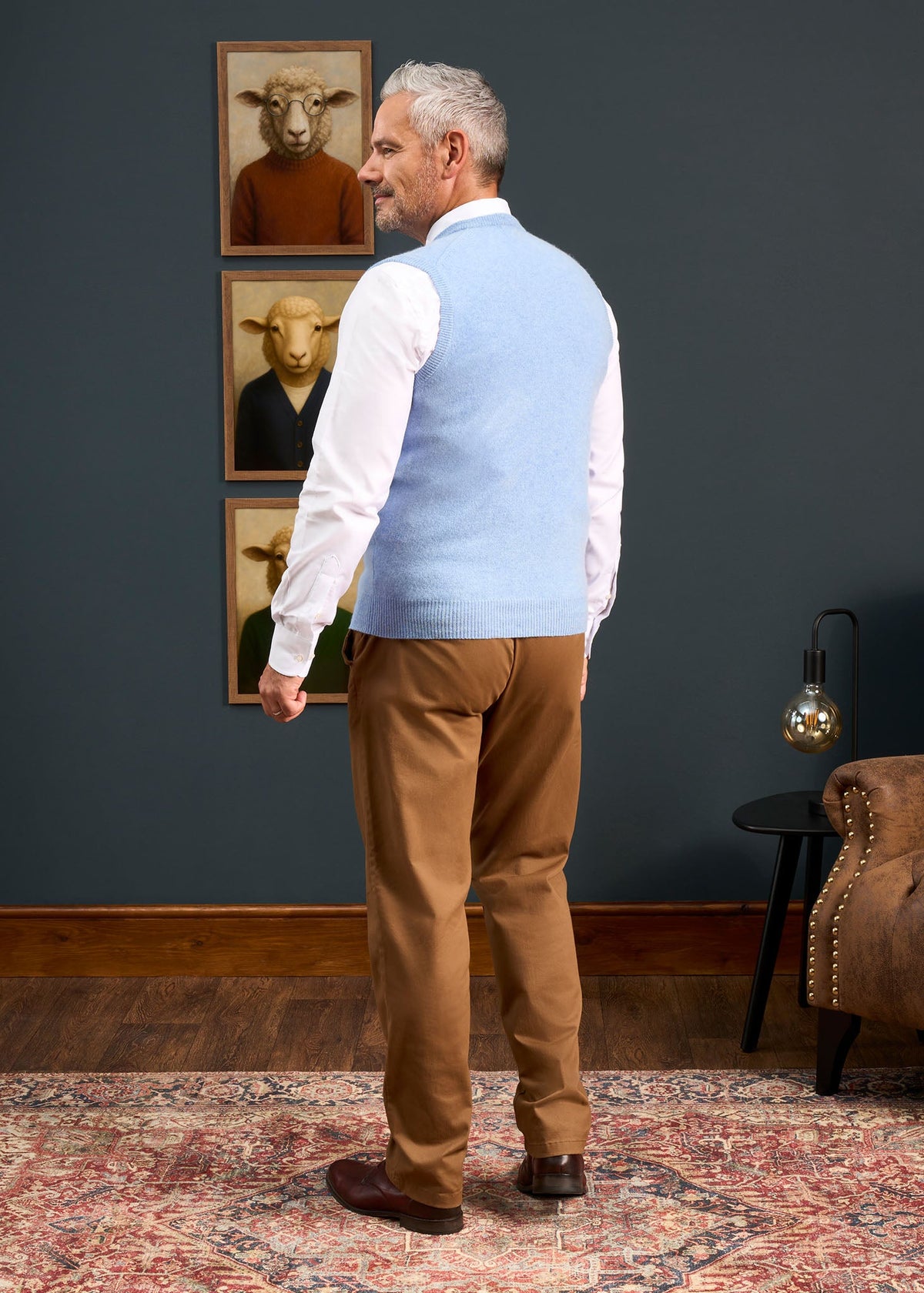 A man seen from behind wearing a Norfolk Lambswool V-Neck Slipover In Glacier over a white shirt and tan trousers.