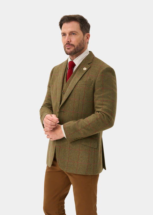 Man in Combrook Men’s Sage Tweed Water Repellent Sports Blazer, red tie, and brown pants stands on white background.