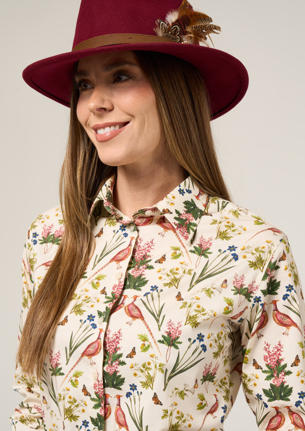 Woman in a maroon feathered hat wears the Lawen Cream Floral Cotton Printed Shirt, looking slightly to the side.