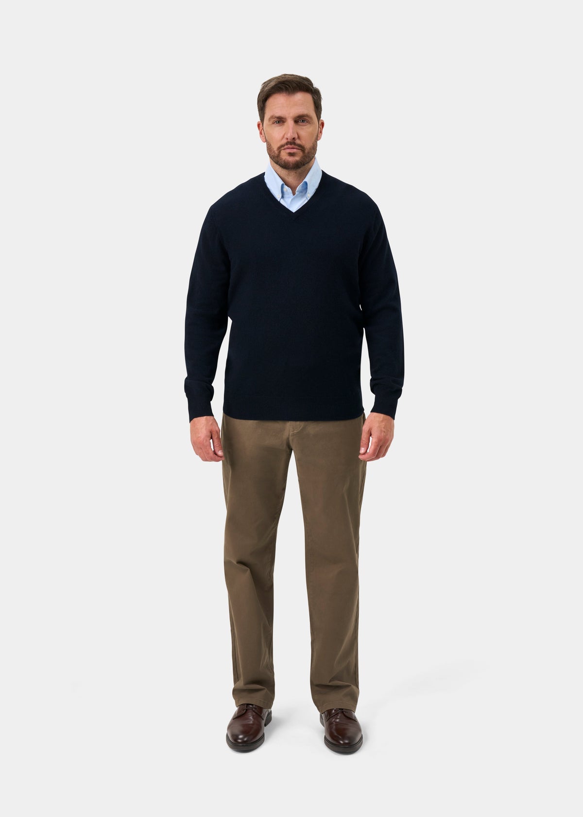 Man wearing Haddington Pure Cashmere V-Neck Jumper in Dark Navy, light blue shirt, khaki pants, and brown shoes.