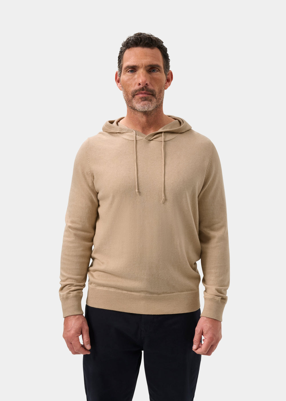 Man in Gaisby Cotton Merino Hoodie in oatmeal and dark pants stands facing forward against a white background.