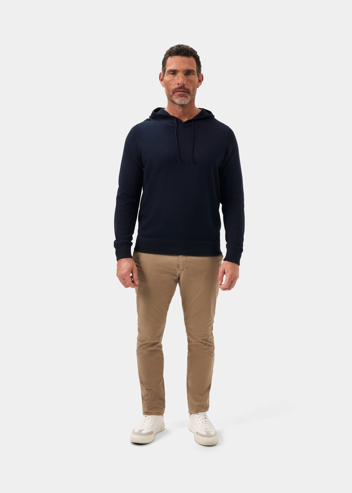 Man wears a Gaisby Cotton Merino Hoodie in Dark Navy, khaki pants, and white sneakers, facing forward.