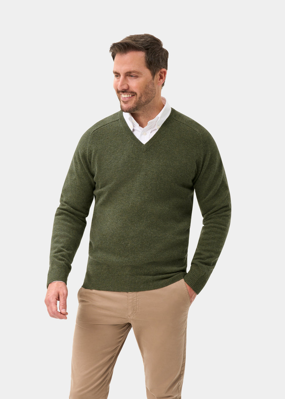 Man in Kilsyth Lambswool V-Neck Jumper in Landscape, over a white shirt and tan pants, smiling against light background.