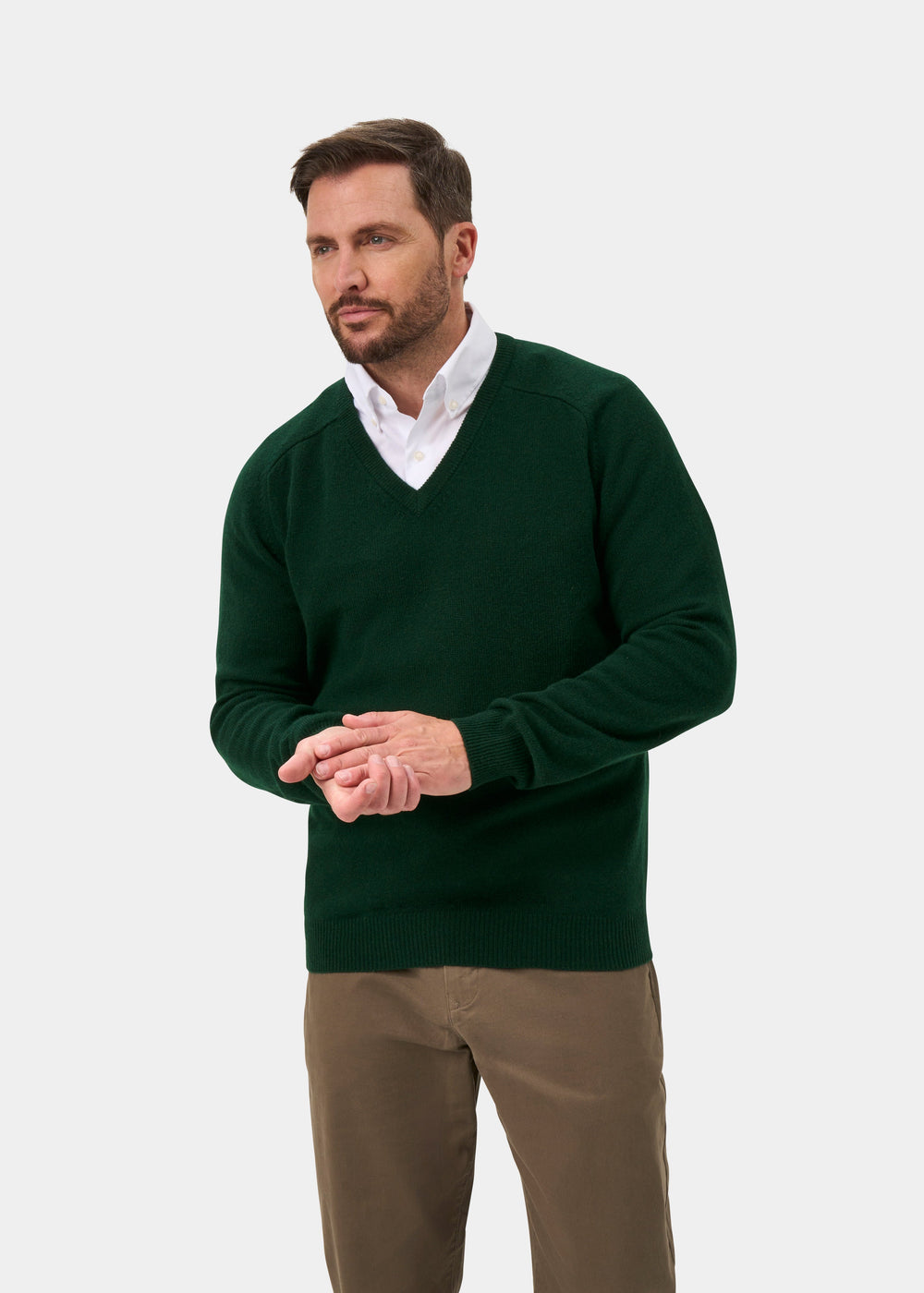 Man wears Hampshire Lambswool V-Neck Jumper in Tartan Green, classic fit, with khaki pants against plain background.