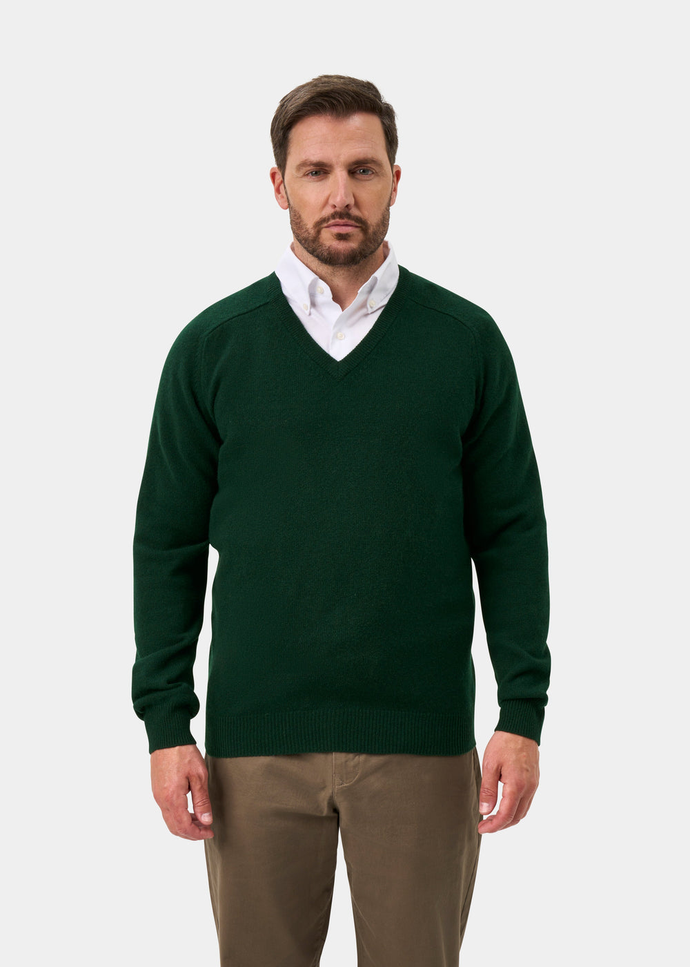 Man wears Hampshire Lambswool V-Neck Jumper in Tartan Green over white shirt and khakis, against a plain background.