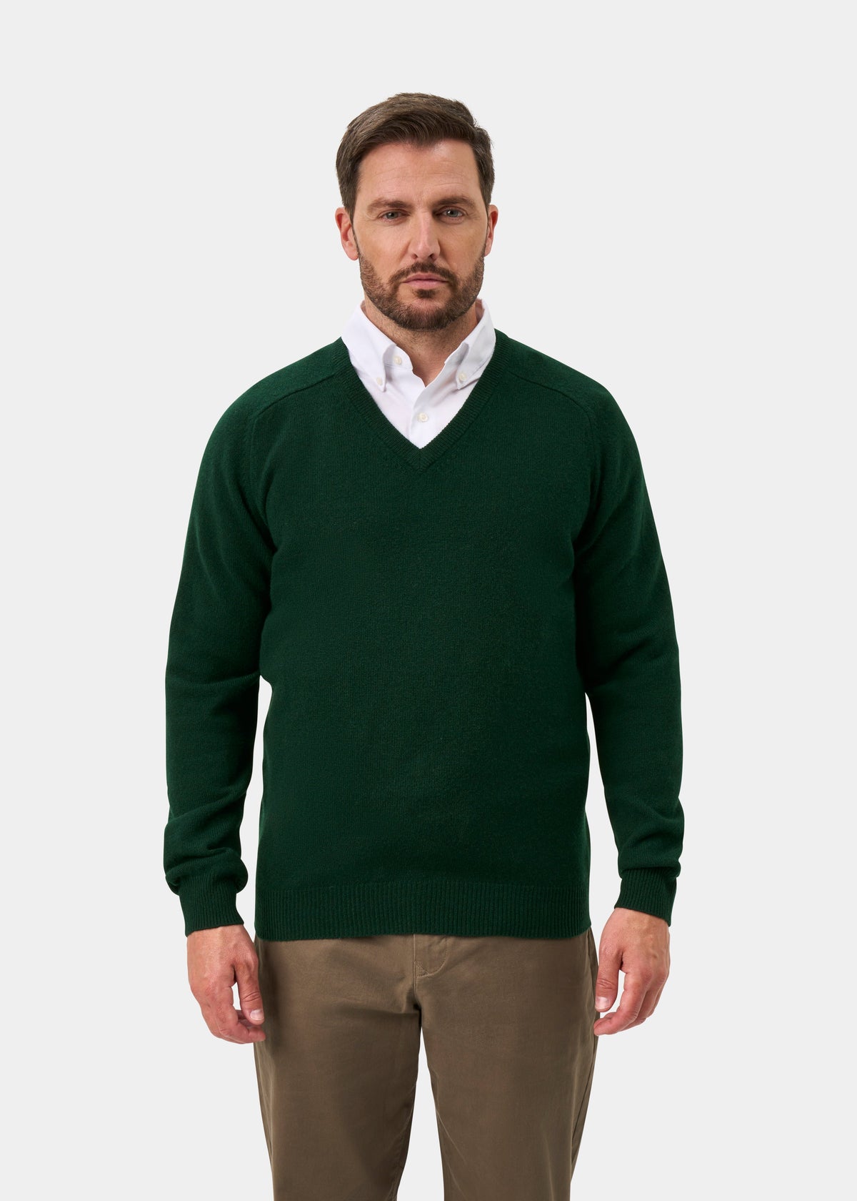 Man wears Hampshire Lambswool V-Neck Jumper in Tartan Green over white shirt and khakis, against a plain background.