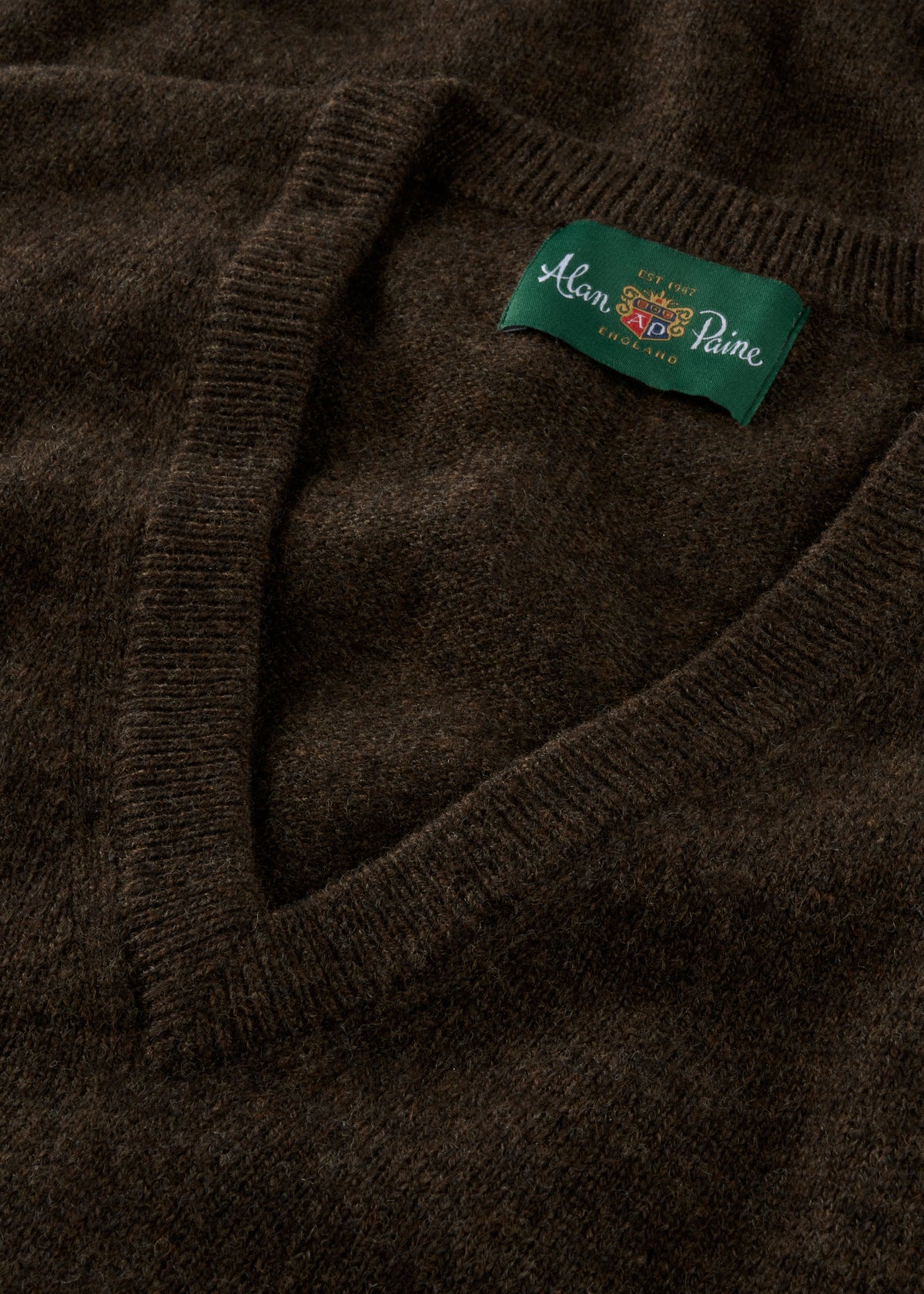 Close-up of a dark brown sweater with a brand label on the collar.