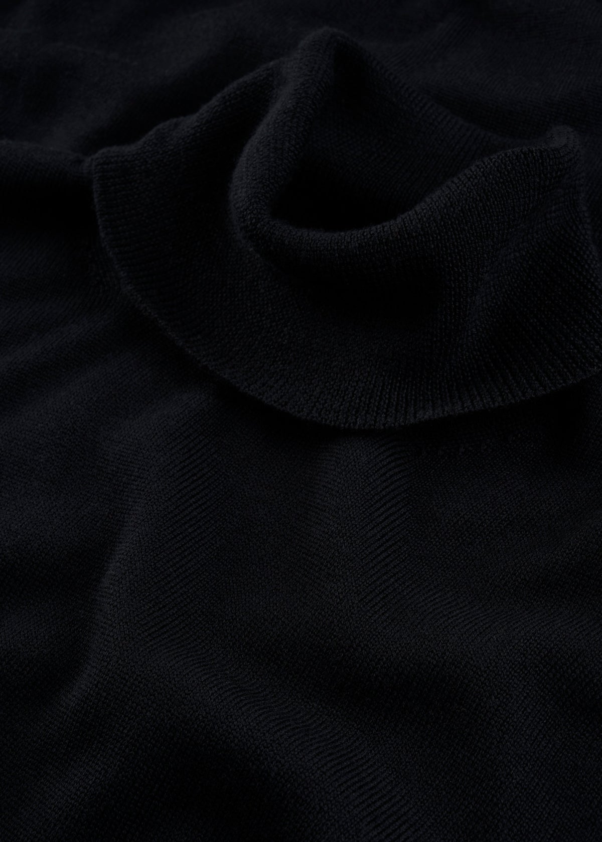 Close-up of the Linton Merino Wool Roll Neck Jumper in black, spotlighting its soft knit collar and stylish design.