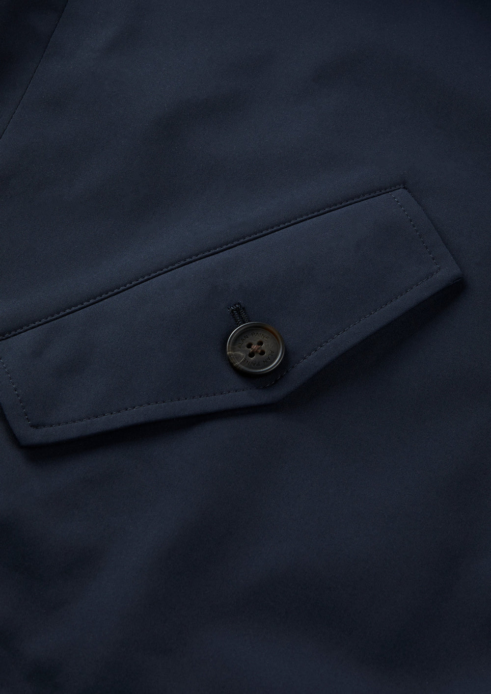 Closeup of Lakeward Men’s Reversible Bomber Jacket in navy, showing pocket flap with round black button.