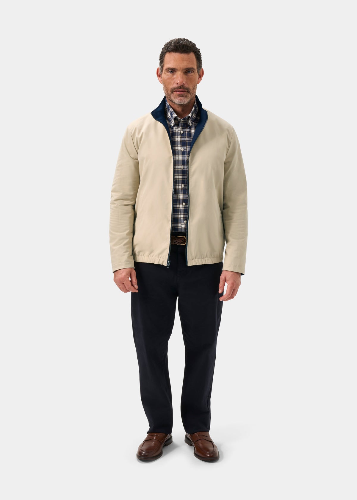 Man in Lakeward Men’s Reversible Bomber Jacket (Navy/Beige), plaid shirt, dark pants, brown shoes on white background.