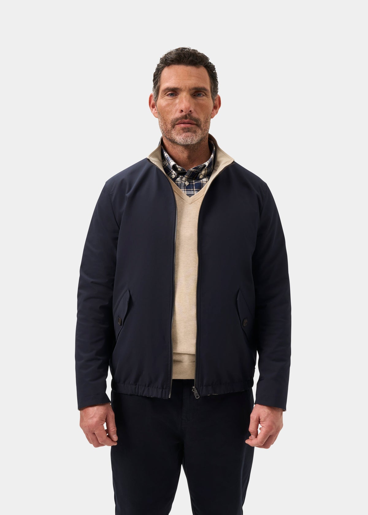 Man wears Lakeward Men’s Reversible Bomber Jacket in navy and beige, facing forward against a white background.