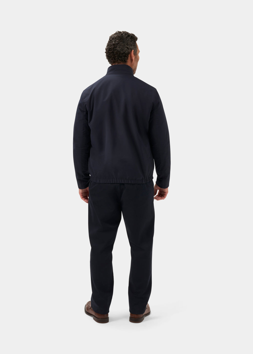 A man faces away in the Lakeward Men’s Reversible Bomber Jacket in navy and beige, with matching pants and brown shoes.