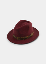 Flat lay of a burgundy wool felt fedora with olive-green leaf band, displayed on a white background.