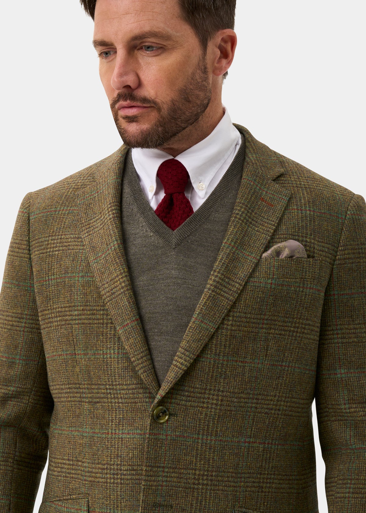 A man wears a Surrey Men’s Tweed Water Repellent Lined Blazer in Marsh over a grey sweater, white shirt, and red tie.