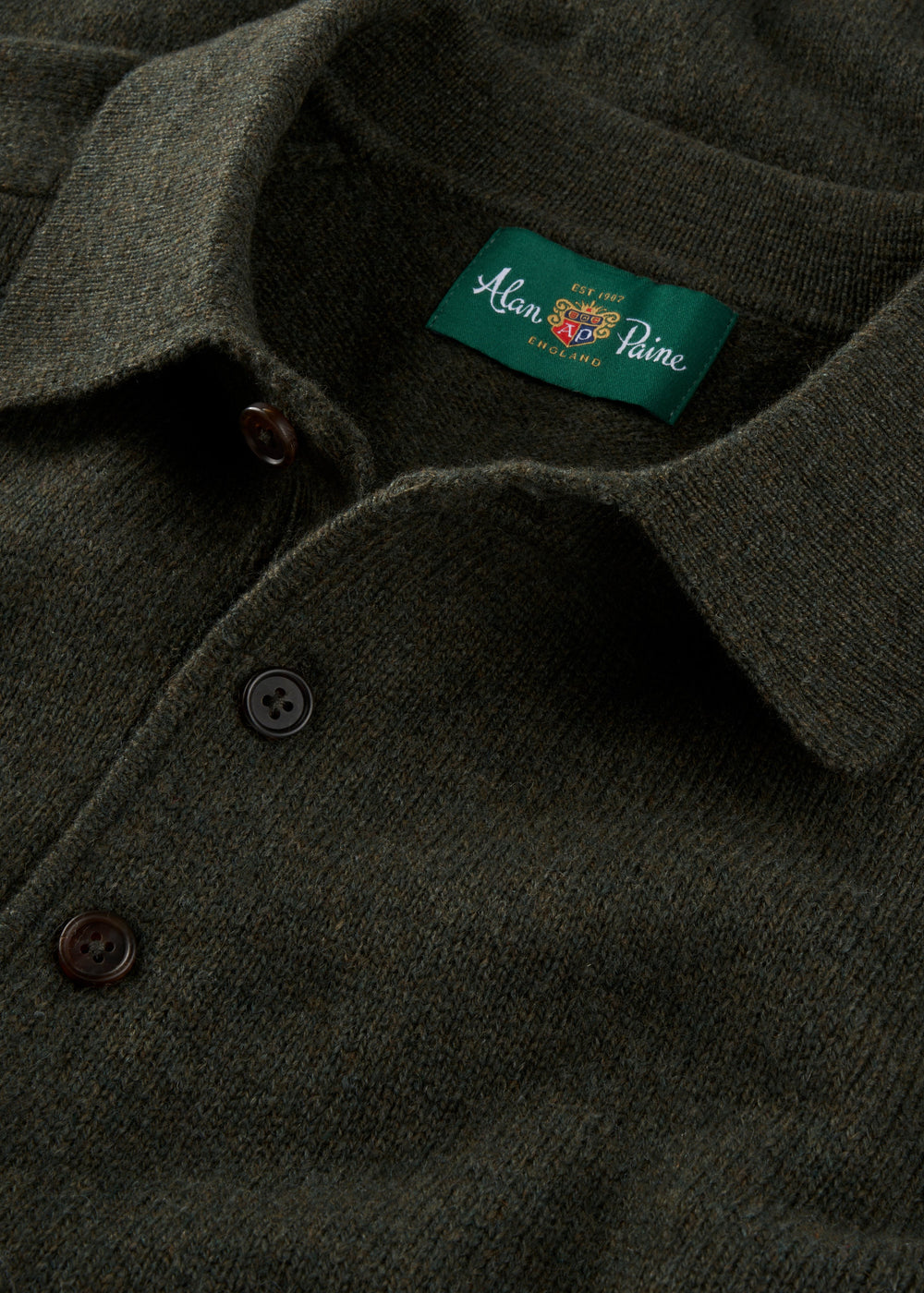 Close-up of a dark green polo shirt with a brand label on the collar.