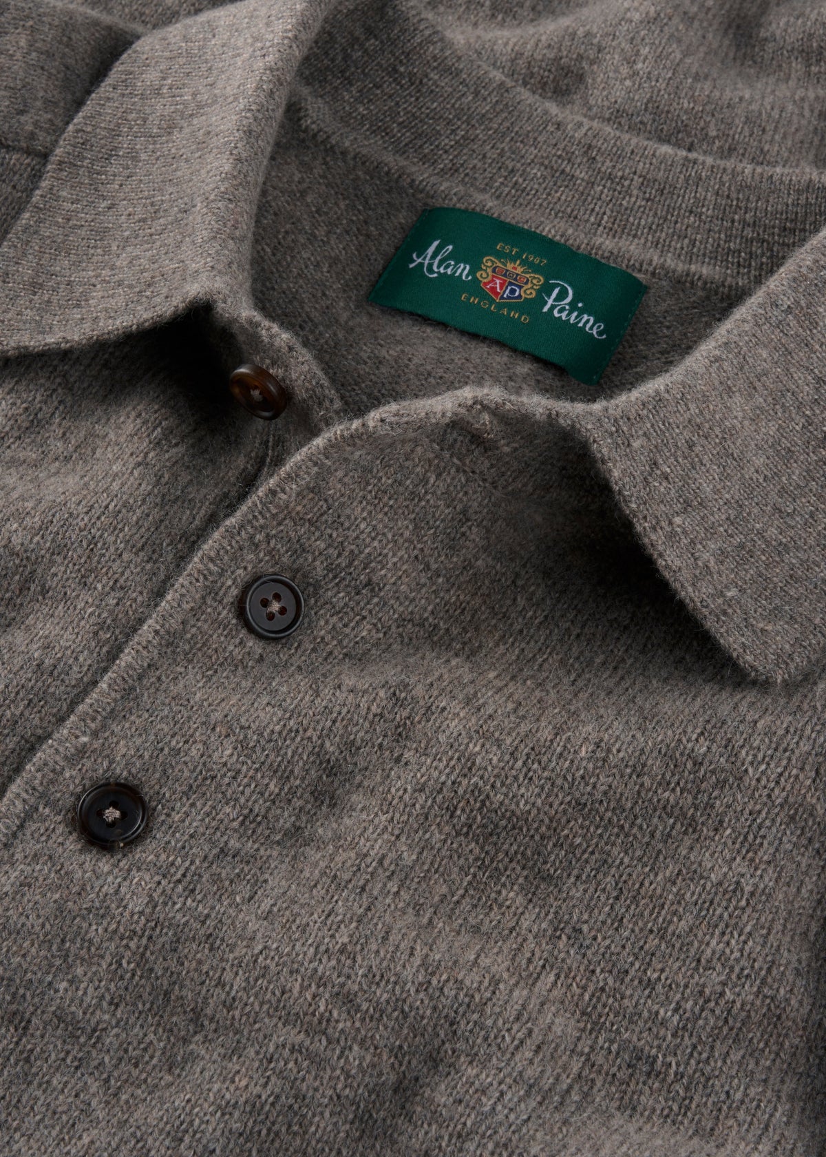 Grey polo shirt with a brand label on a close-up of the collar.