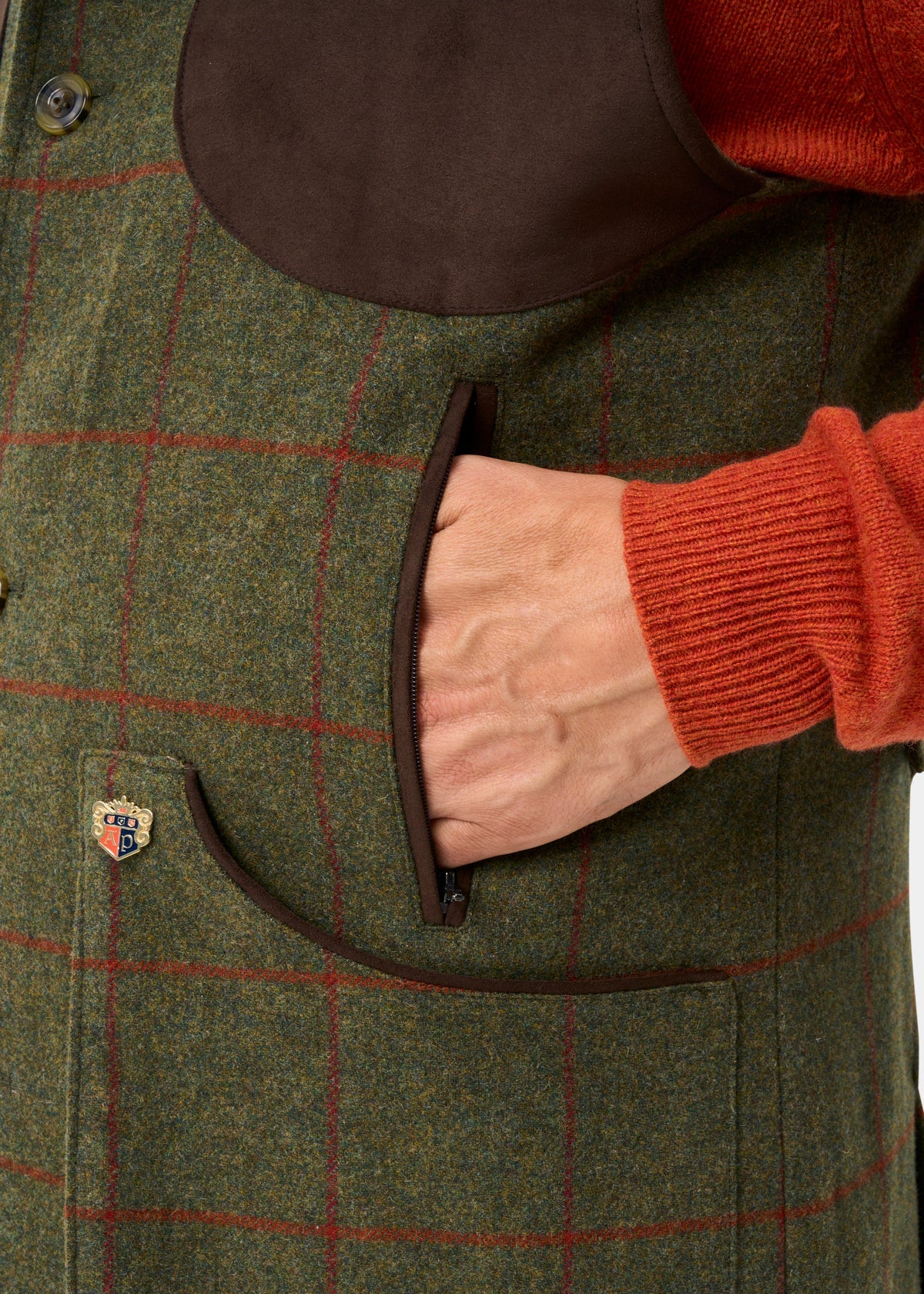 A close-up of a person in a Combrook Men’s Tweed Shooting Gilet in Reed with suede shoulder patch and red checks.