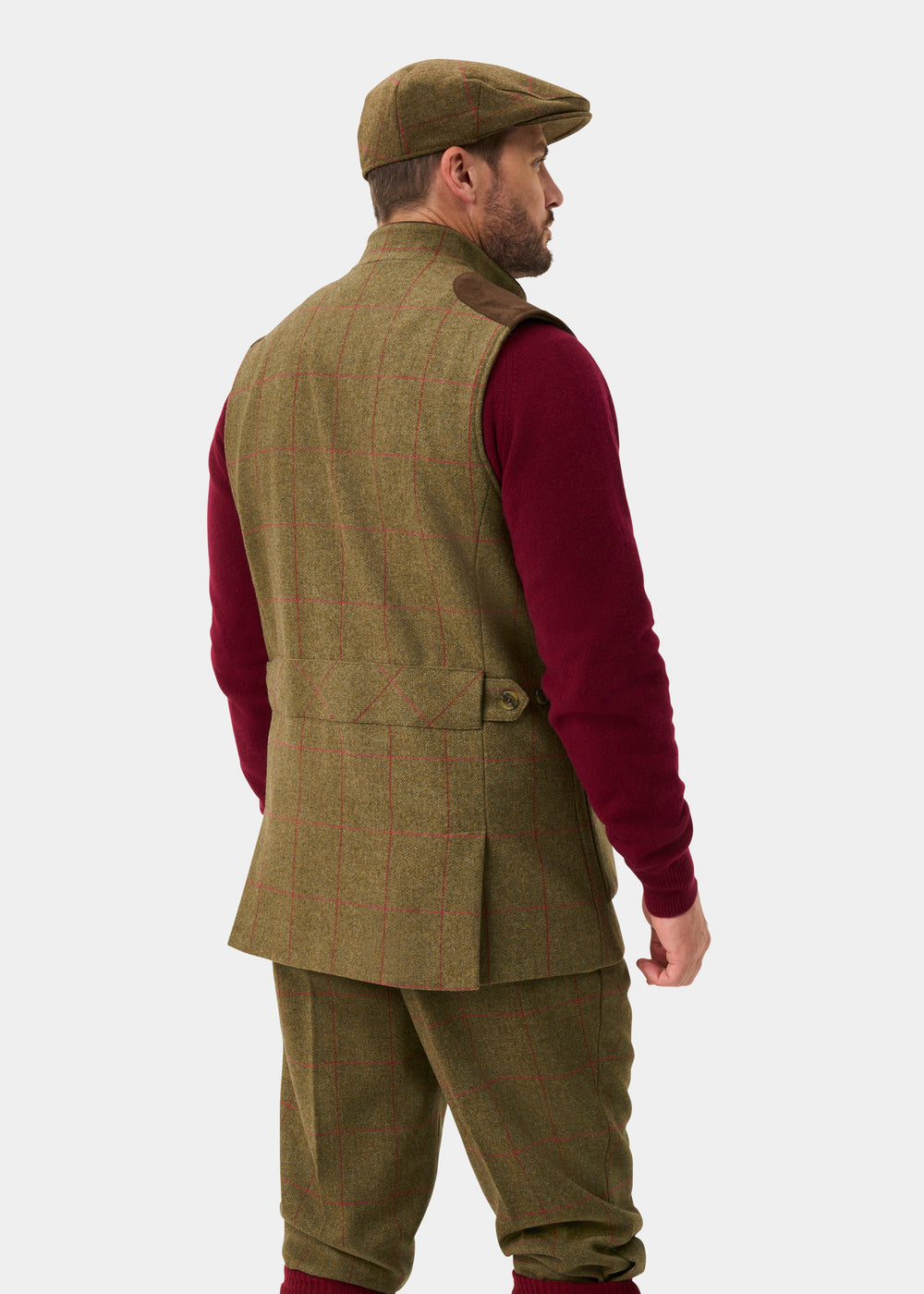 Man in green plaid suit, red sweater, flat cap, wearing Combrook Men’s Sage Tweed Shooting Gilet, facing away.