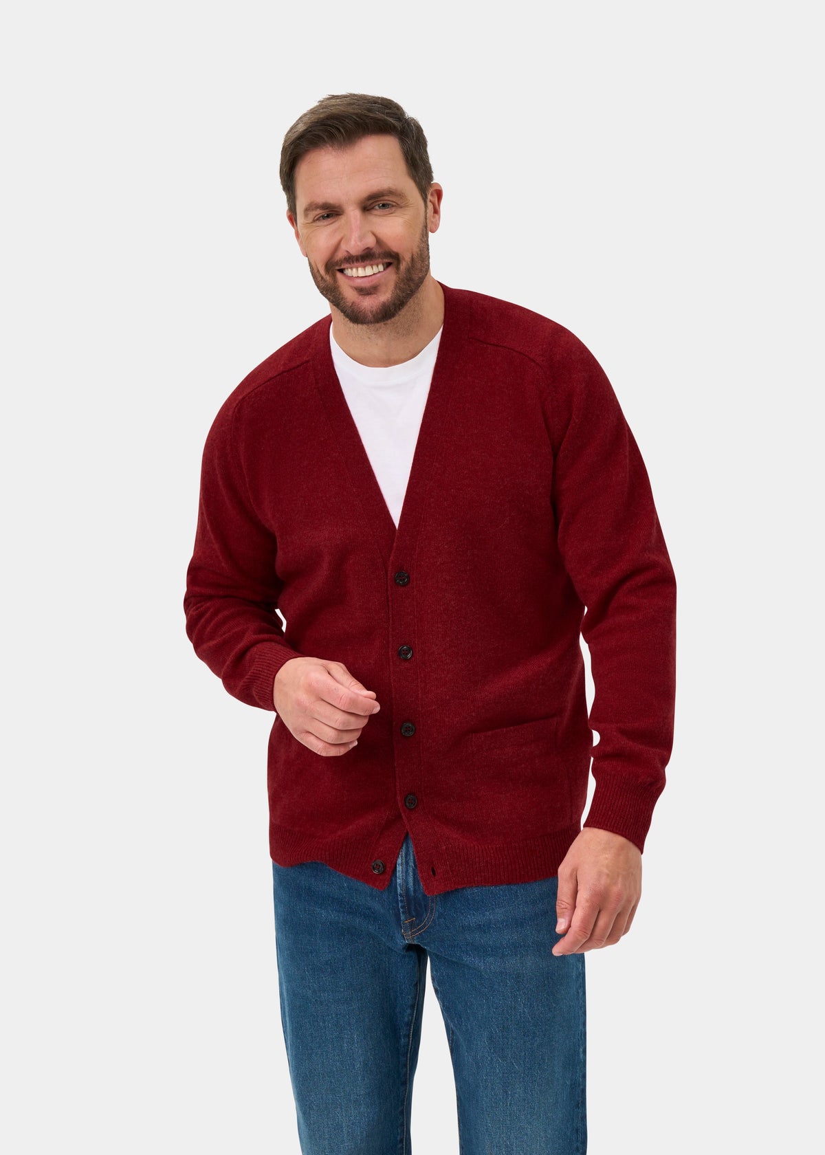 Man smiling in Cornwall Lambswool V-Neck Cardigan in Poppy Melange, over white tee and blue jeans, plain background.