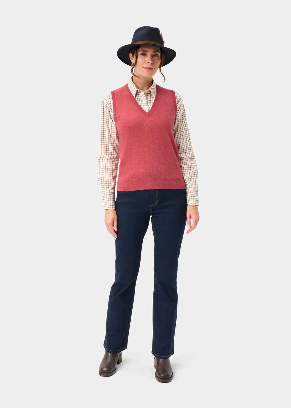 Woman in hat, Erin Wool & Cashmere V-Neck Slipover in Rouge, plaid shirt, dark jeans, and boots on plain background.
