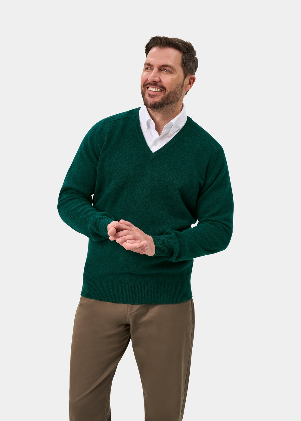 Man in Hampshire Lambswool V-Neck Jumper in Mallard, classic fit, and khaki pants, smiling on white background.