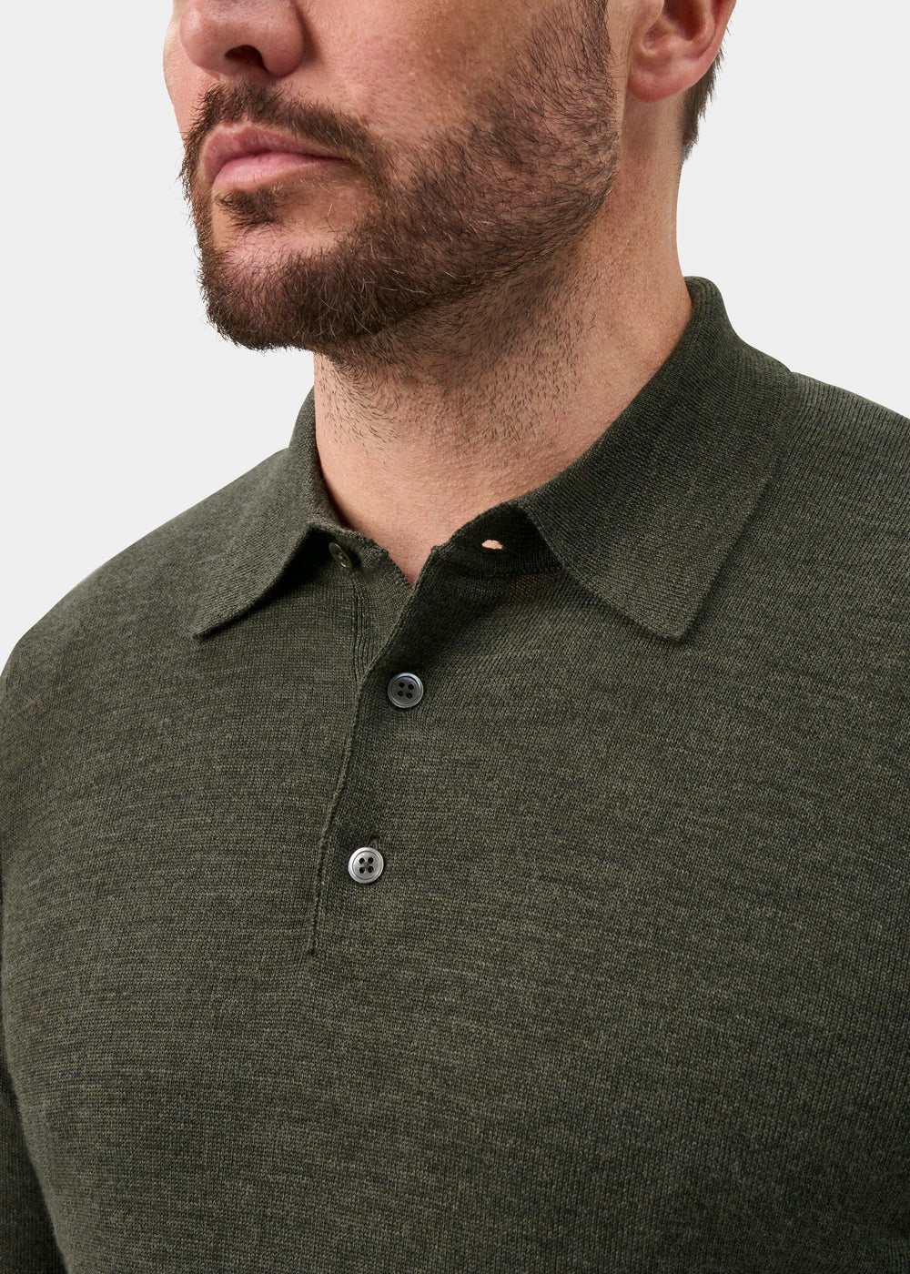 Man wearing Hindhead Men’s Merino Wool Polo Shirt in Seaweed, regular fit; shoulders to nose on white background.