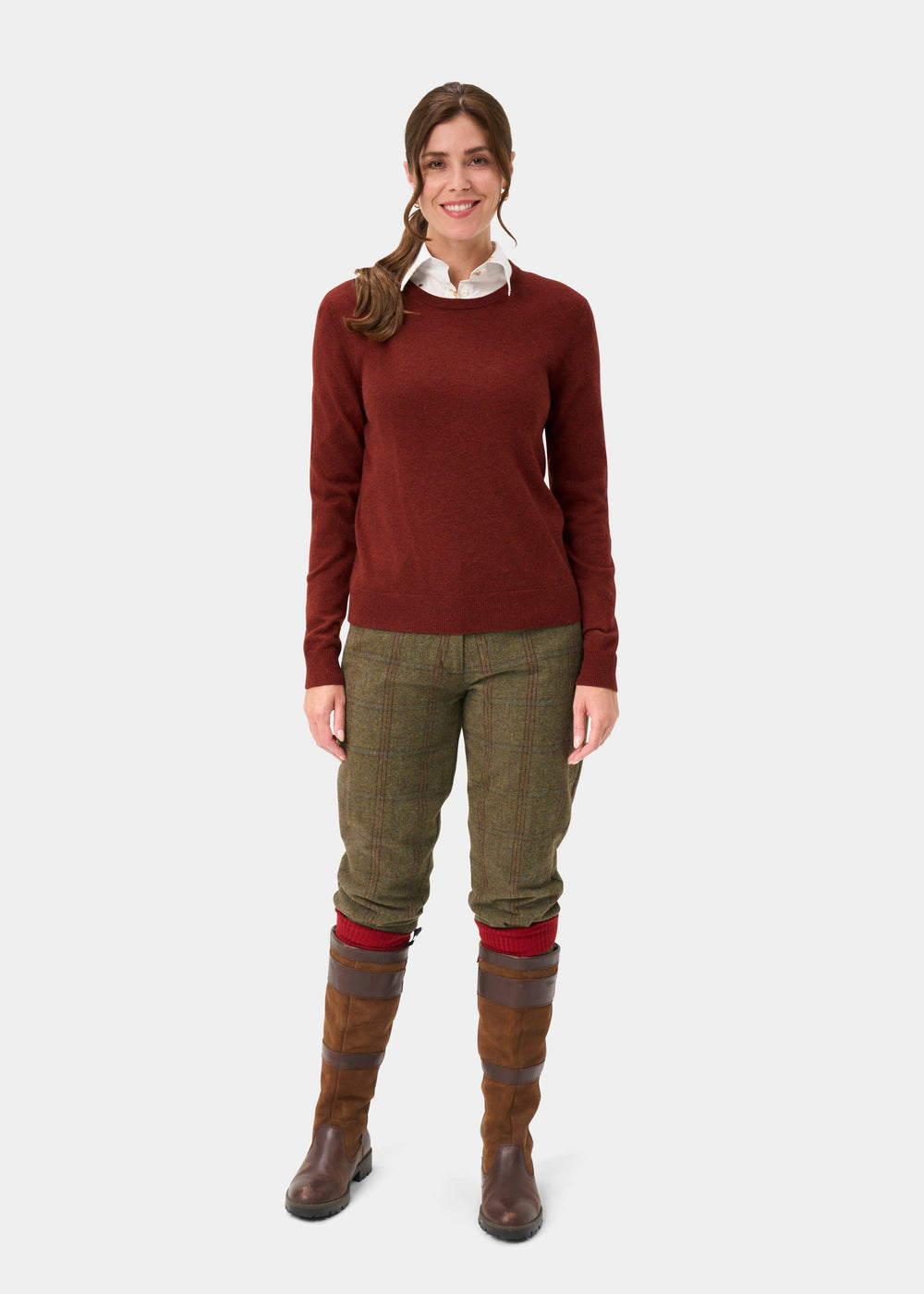 Woman in Ivy Wool & Cashmere Crew Neck Jumper In Autumn smiles in checked pants and brown boots against white backdrop.
