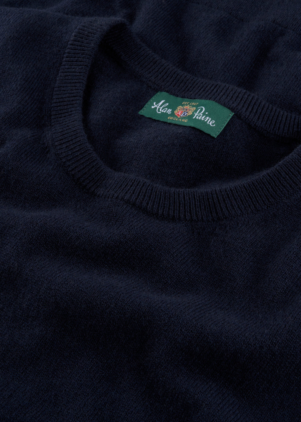 Close-up of a dark blue sweater with a brand label on the collar.