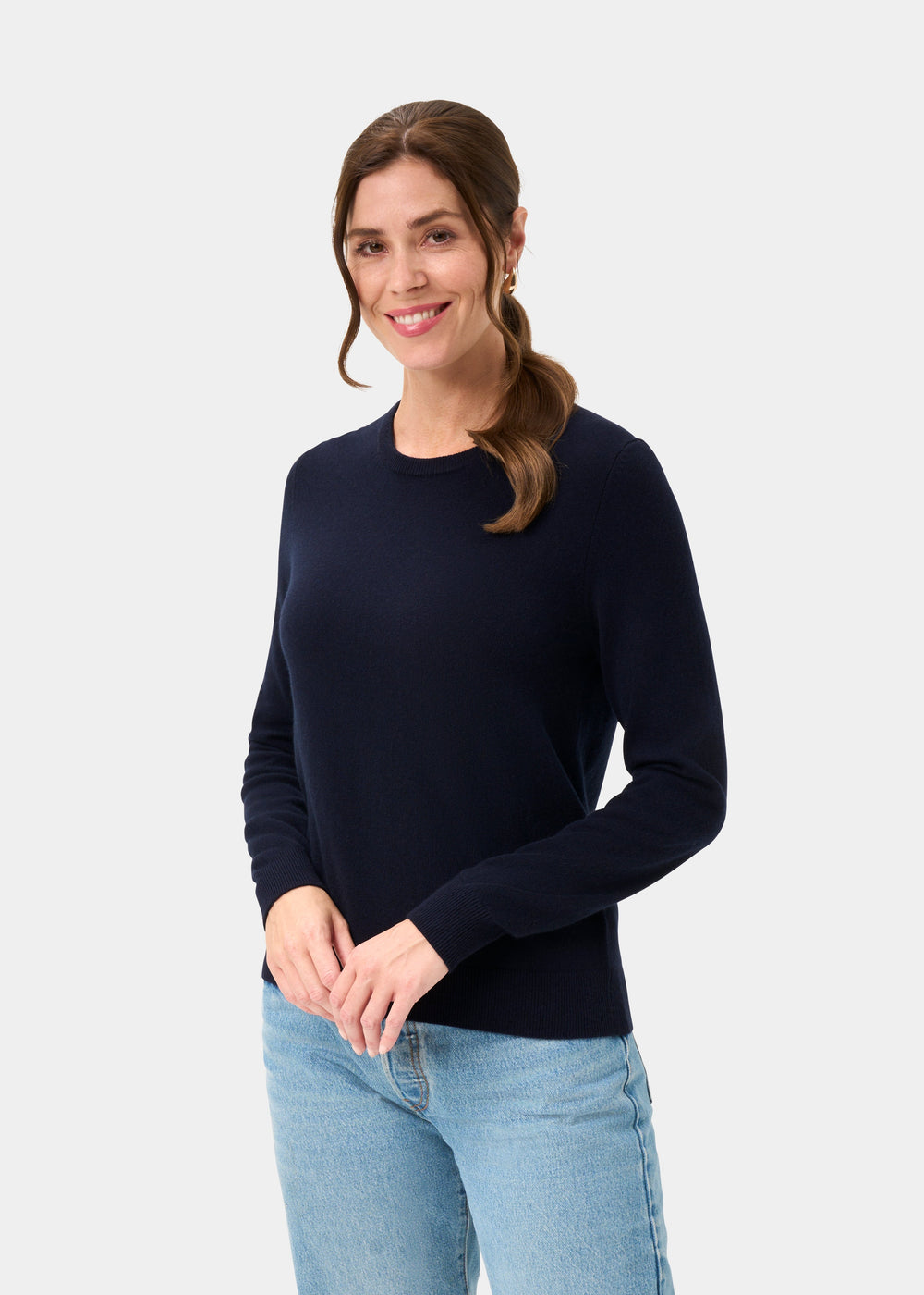 Woman with brown hair wears the Ivy Wool & Cashmere Crew Neck Jumper in Dark Navy and light blue jeans, smiling.
