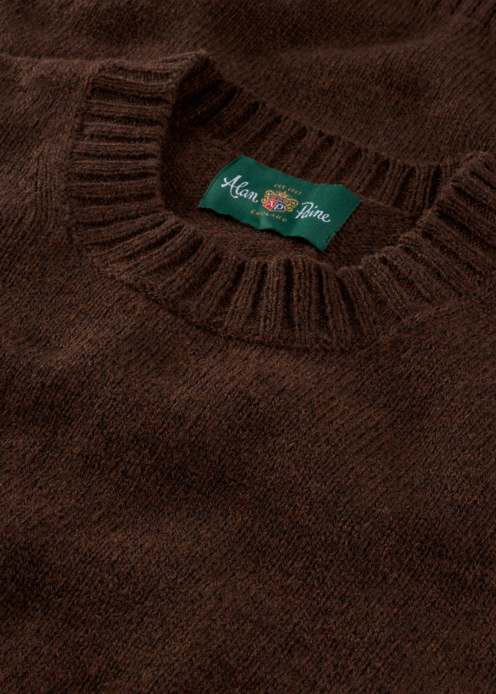 Close-up of the Kinnadie Supersoft Shetland Wool Crew Neck Jumper in Coffee, regular fit, with ribbed collar and label.