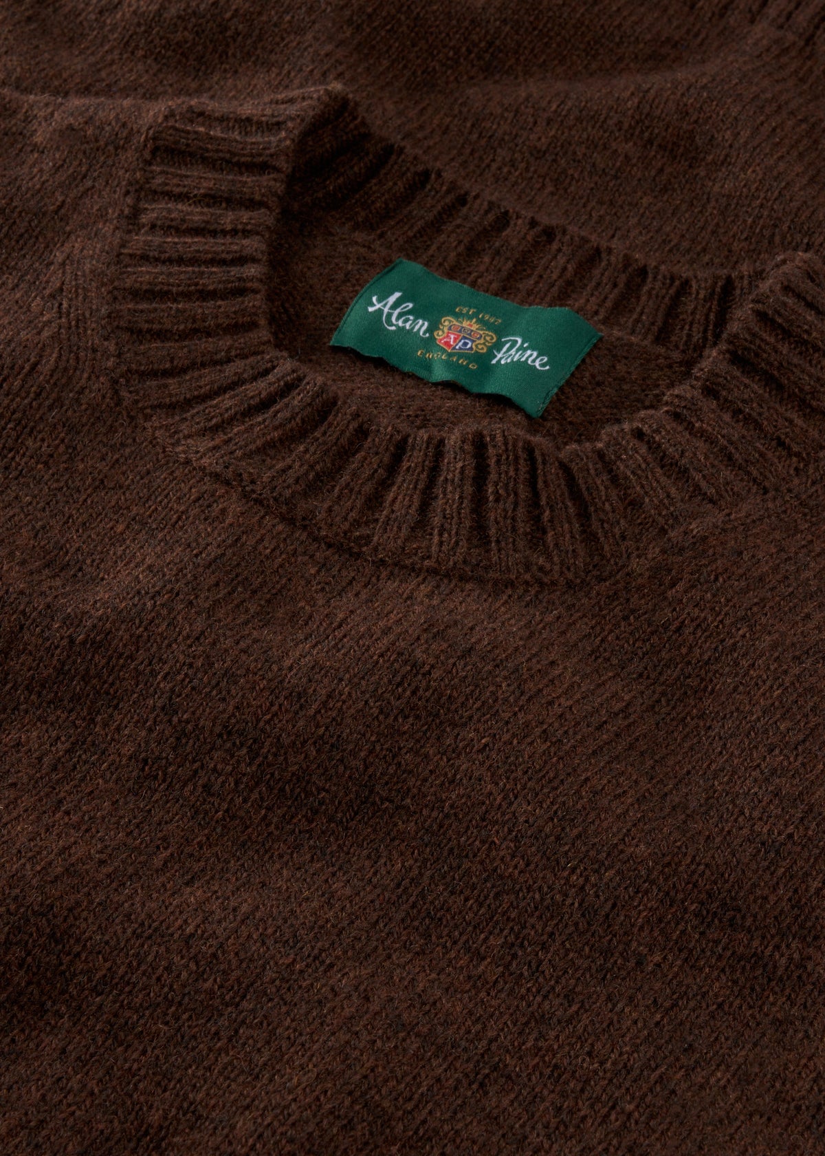 Close-up of the Kinnadie Supersoft Shetland Wool Crew Neck Jumper in Coffee, regular fit, with ribbed collar and label.
