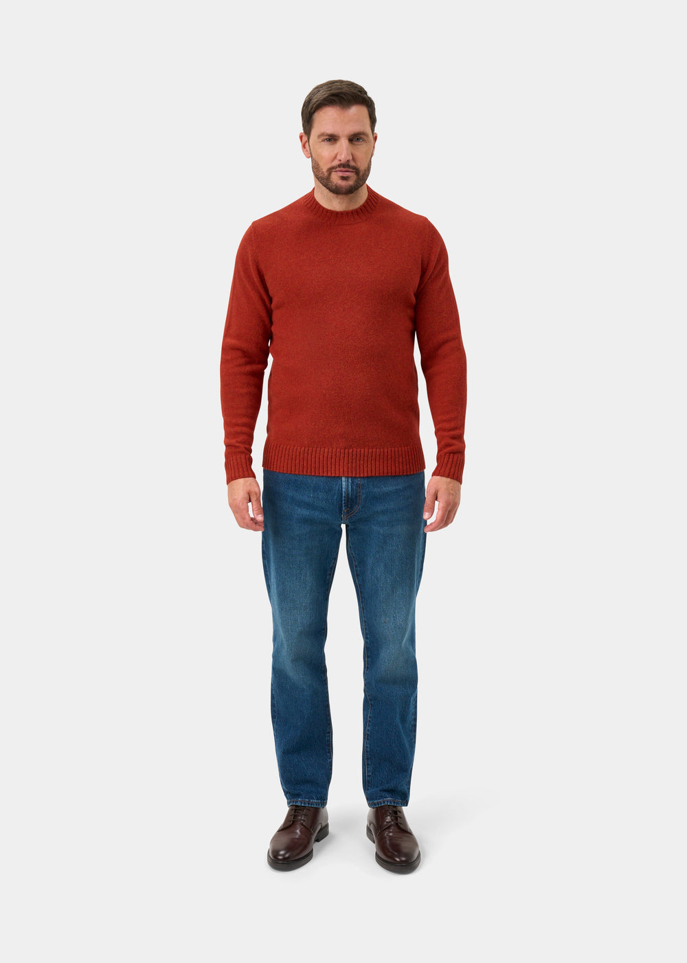 Man in a Kinnadie Supersoft Shetland Wool Crew Neck Jumper in saffron, blue jeans, and brown shoes on white backdrop.