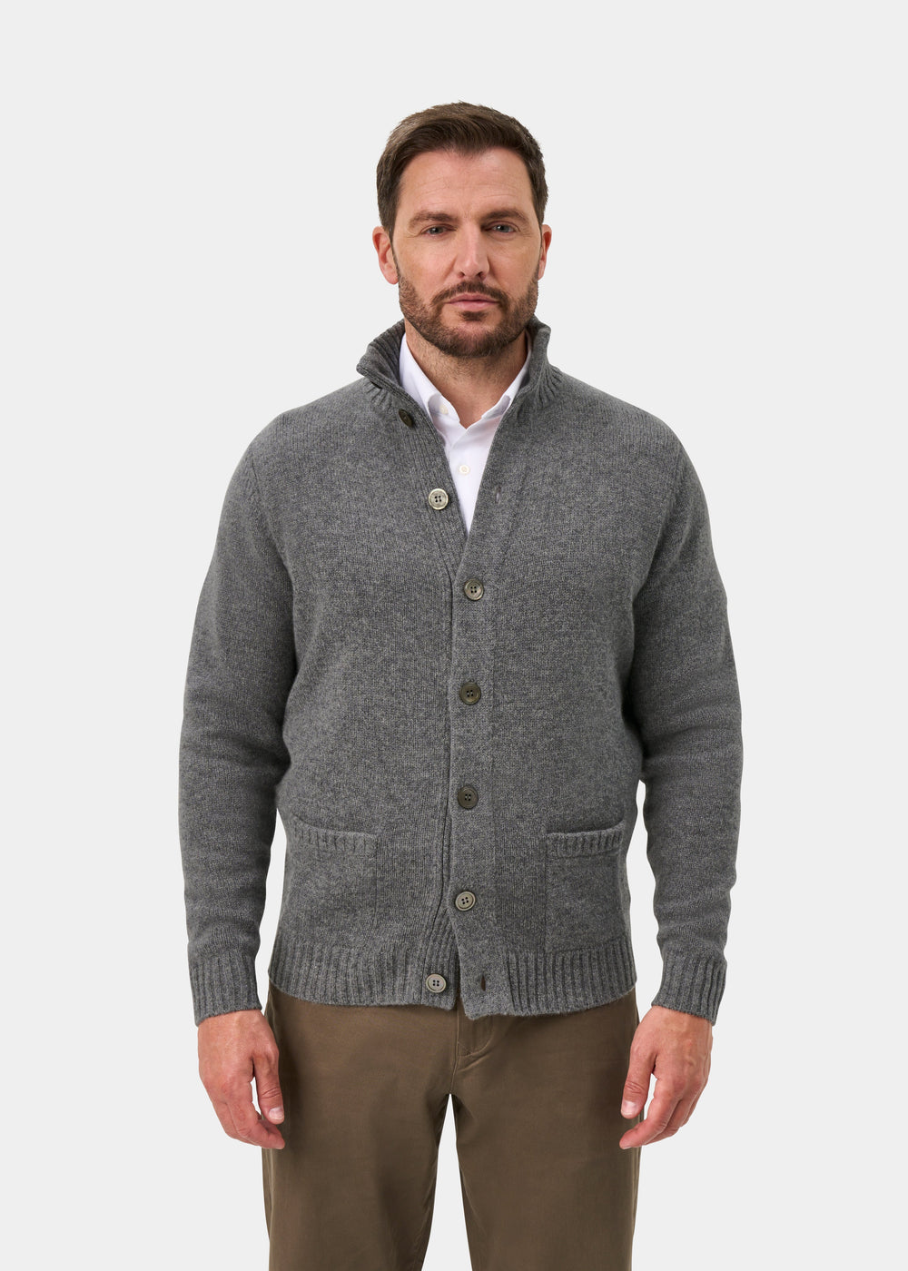 Man in a grey mix Landford lambswool jumper over a white shirt and brown pants, standing against a white background.