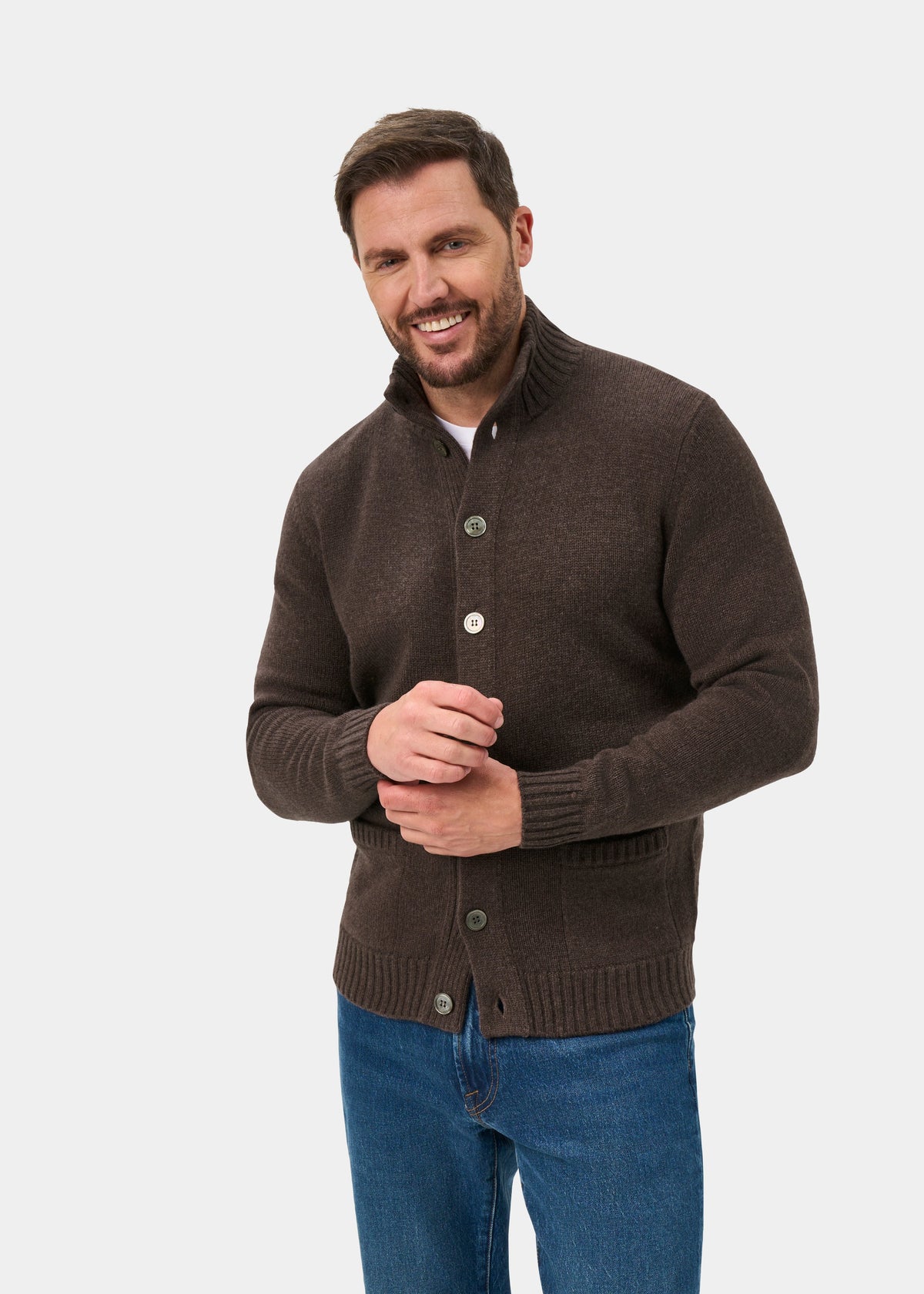 Man smiling in a mocha Landford Lambswool Buttoned Mock Neck Jumper and blue jeans, against a white background.